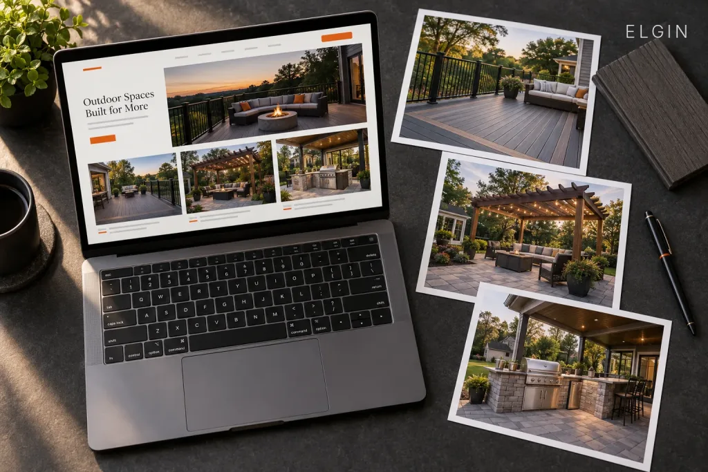 Overhead view of a laptop showing an outdoor living website next to printed photos of a deck, pergola patio, and outdoor kitchen, labeled Elgin, IL