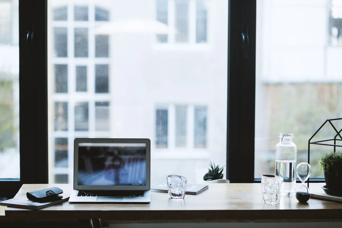 A modern office desk with a laptop and glass of water, symbolizing a professional space for digital marketing.