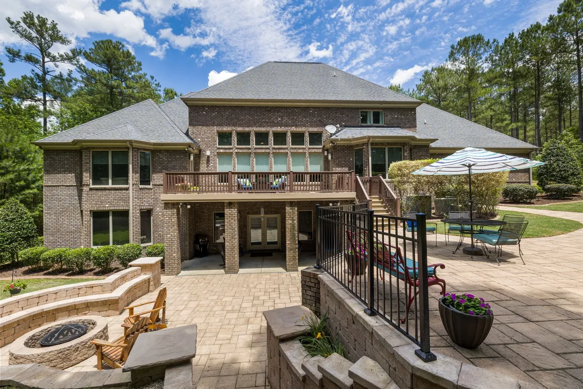 A luxury brick house with a large terrace, fire pit, and a well-kept garden, showcasing quality craftsmanship.